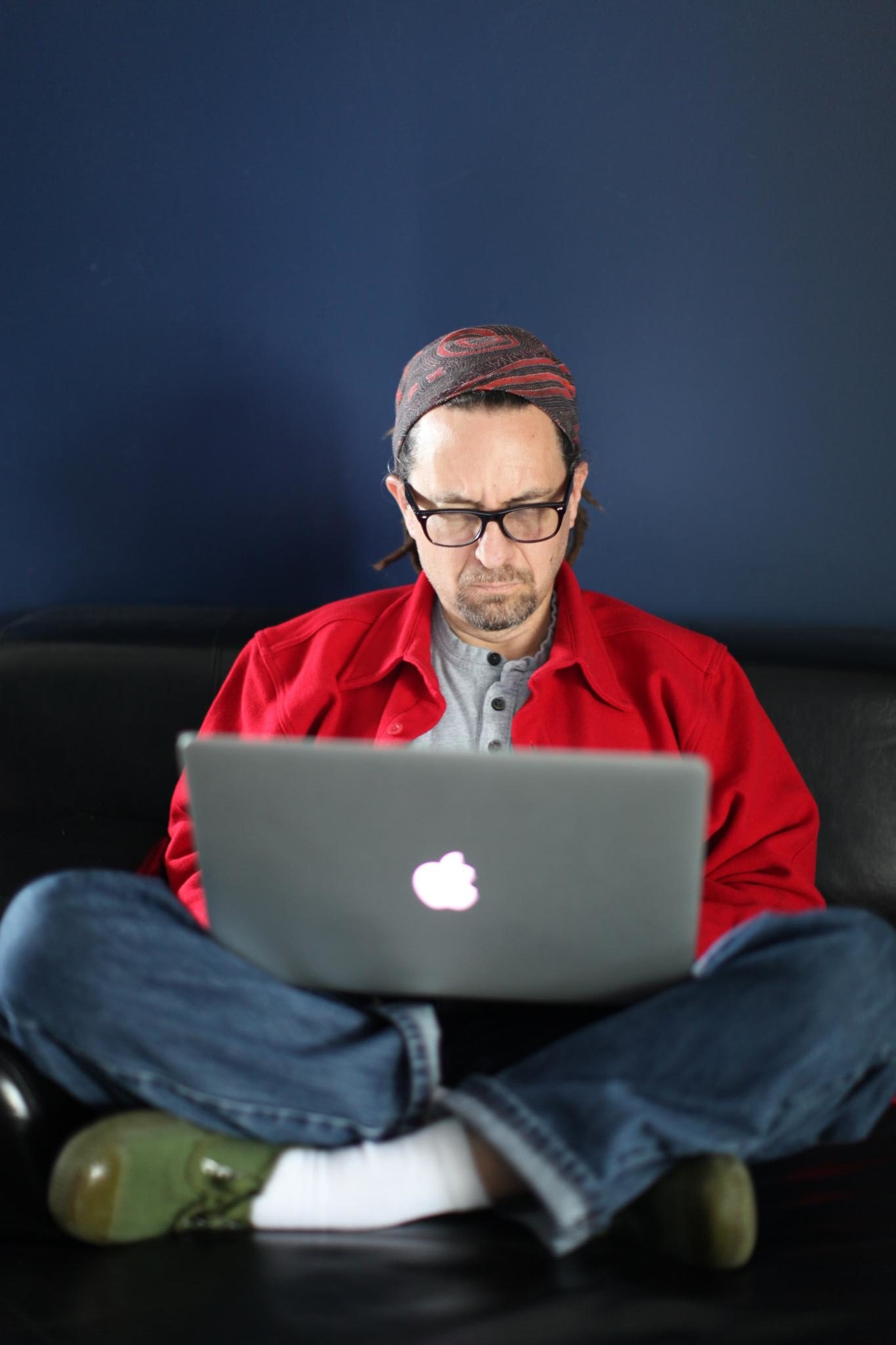 Man sitting on a couch working on a Macbook
