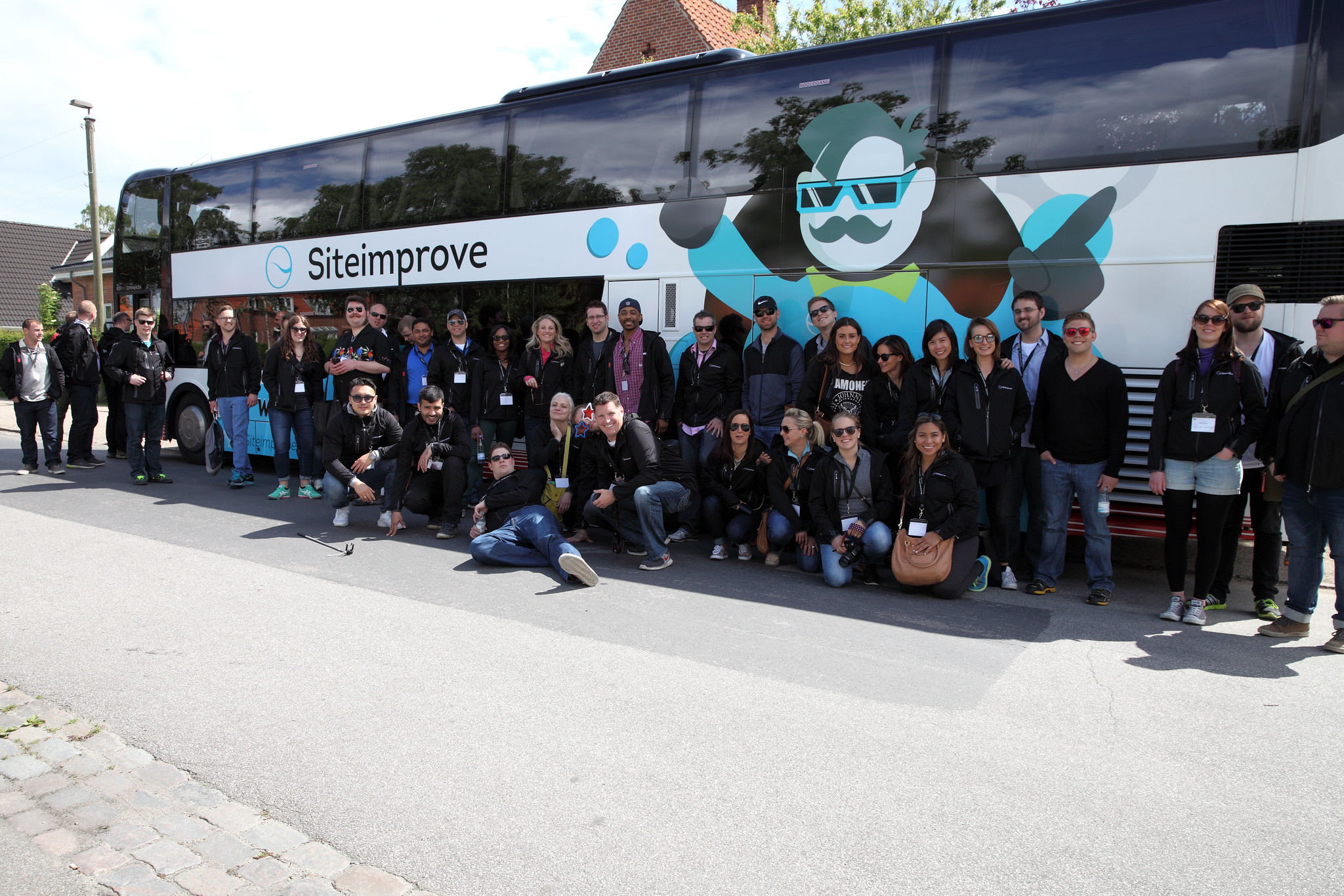 Group of Siteimprove employees posing in front of branded bus on GAAD 2015