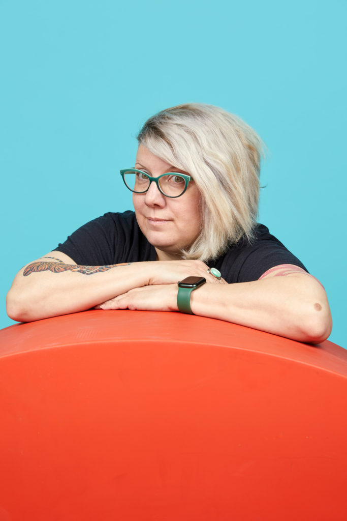 Sharyn, leaning on a piece of orange furniture