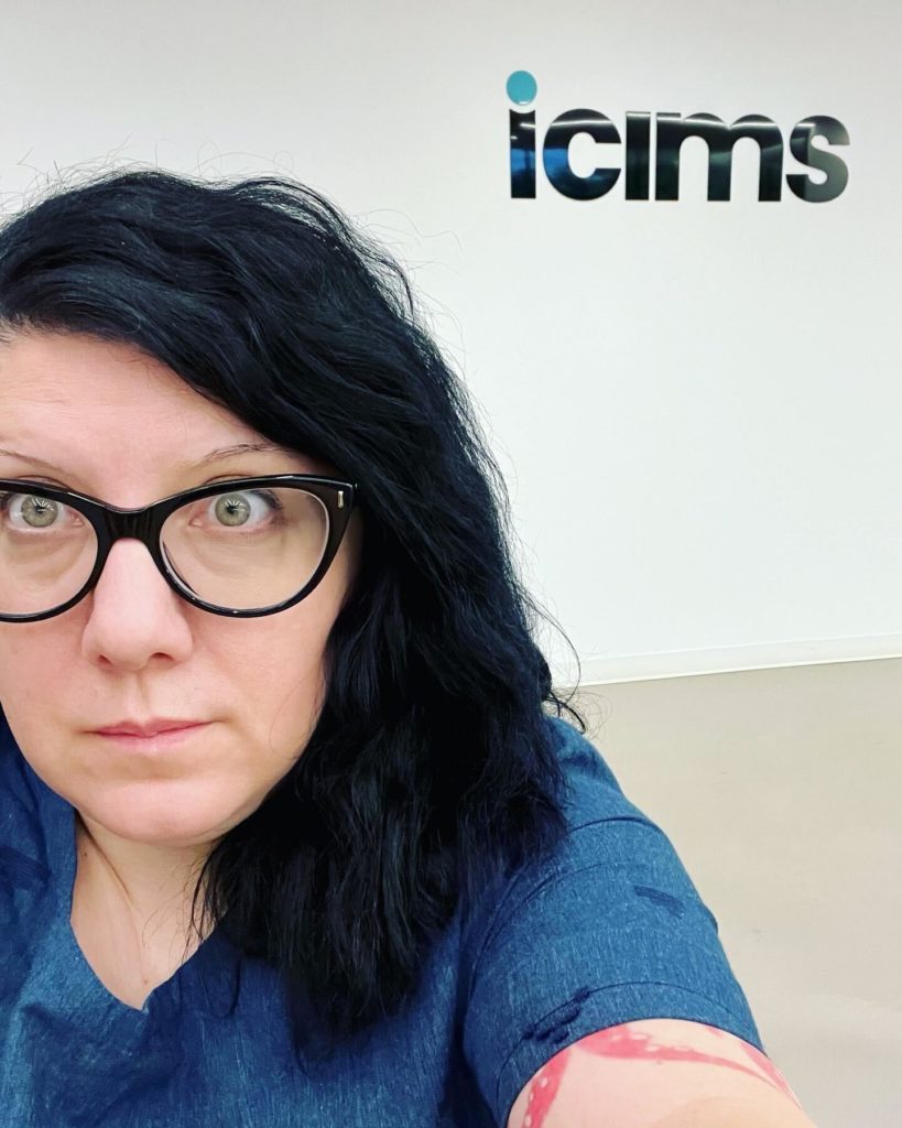 Self, posing in the office with the icims logo behind me