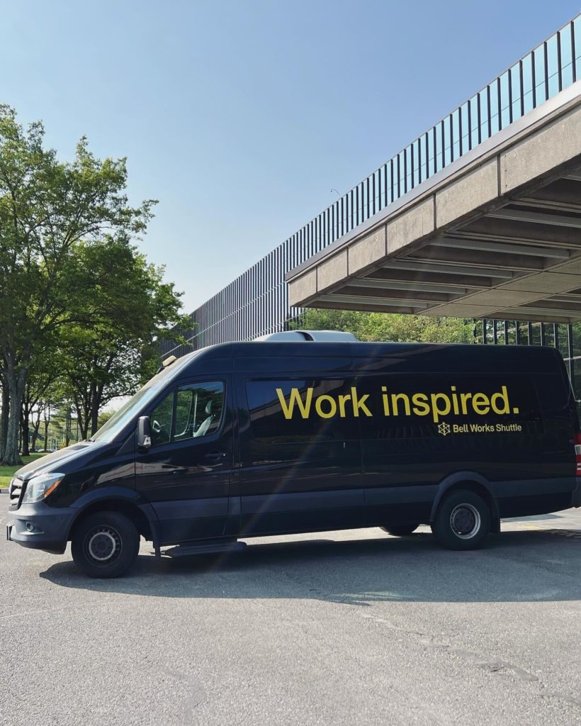 A Bell Works shuttle van outside of the building on a sunny day