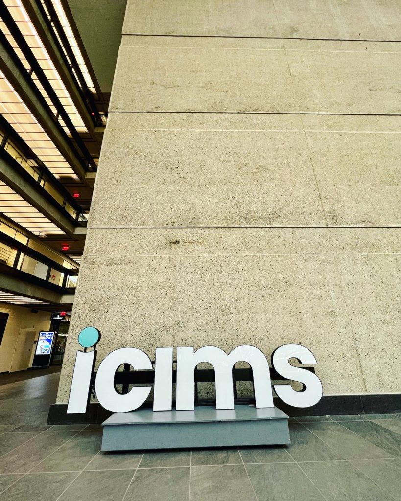 Lobby inside the Bell Works building featuring a large icims sign in white letters against a concrete wall