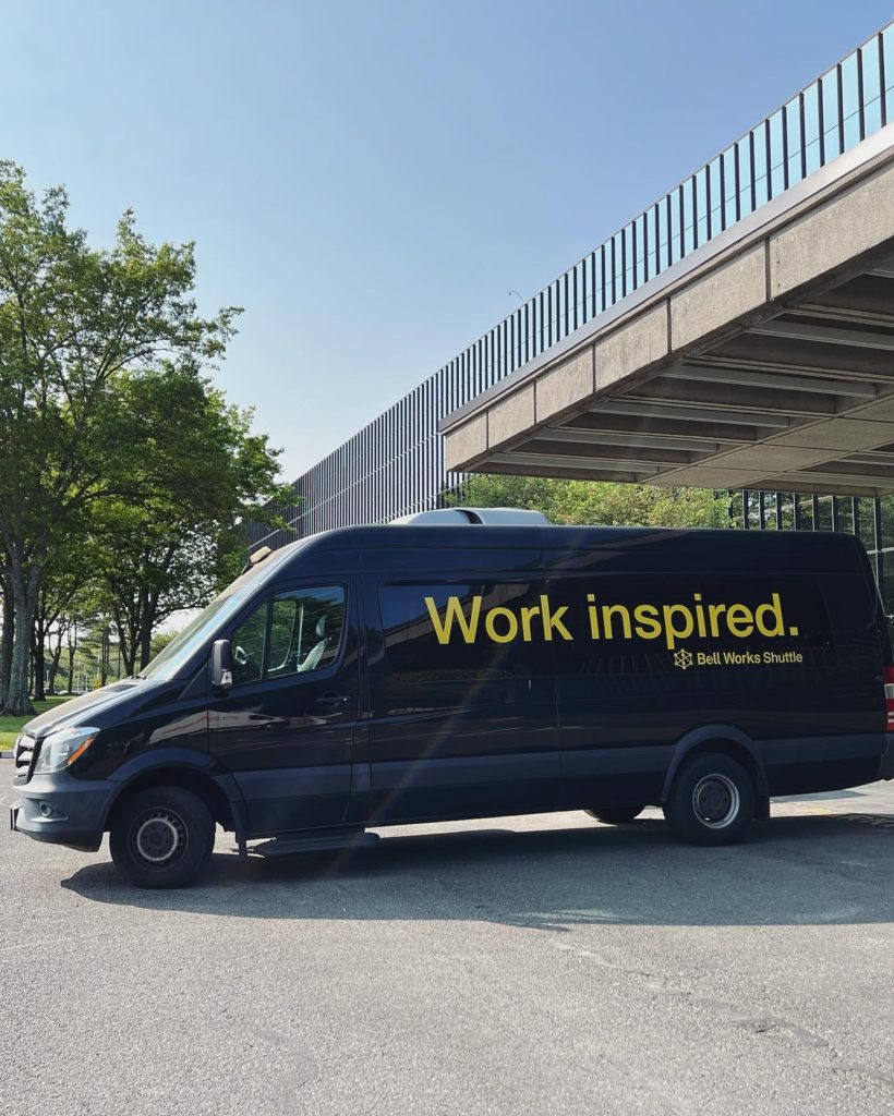 A black van outside of the Bell Works building with yellow lettering reading Work inspired